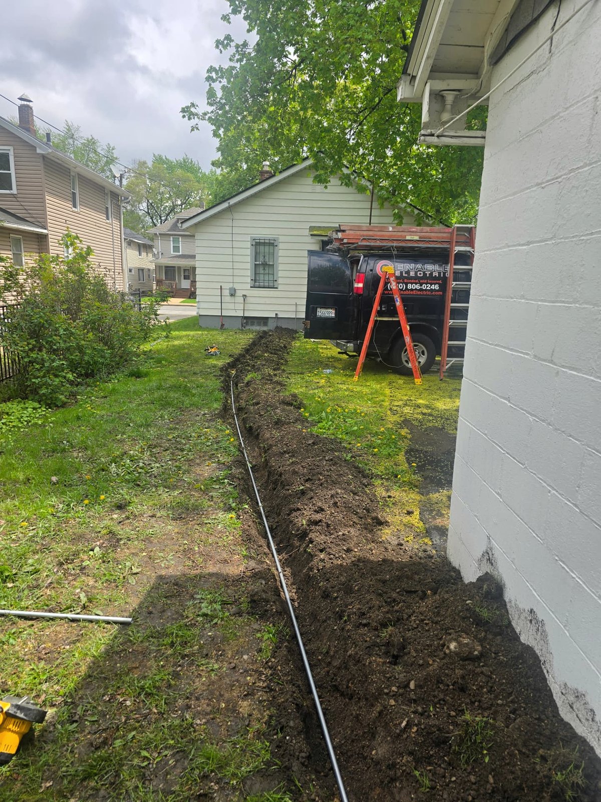 Open trench with underground feeder run beside a detached garage