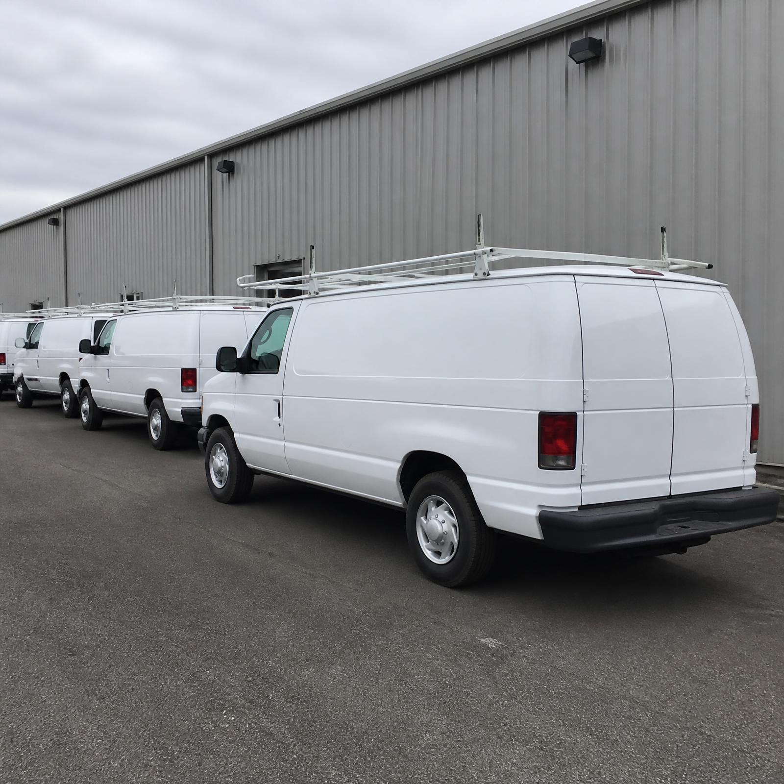 Enable Electric service vans with ladder racks parked outside a commercial building